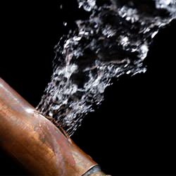 A bursting copper pipe in North Vancouver, with water gushing out.