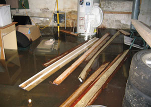 A severely flooding basement in Burnaby, with lumber and personal items floating in a foot of water