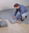 Contractors installing basement subfloor tiles and matting on a concrete basement floor in Coquitlam, British Columbia