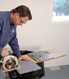 installing a waterproof vapor barrier on a basement floor to prepare for basement carpeting in a North Vancouver home